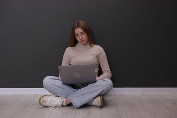 Cyber bullying. Upset teenage girl with laptop on floor indoors