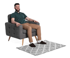 Smiling man relaxing on armchair and rug against white background