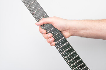 Close-up of a hand on an electric guitar, strings being pressed Six-string instrument with frets,...