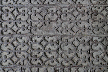 Close-up of weathered, intricate geometric metal design with brown color palette and soft shadows.