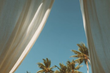 Cozy beach cabana with white linen curtains offering a relaxing view of palm trees and clear blue skies during a sunny day
