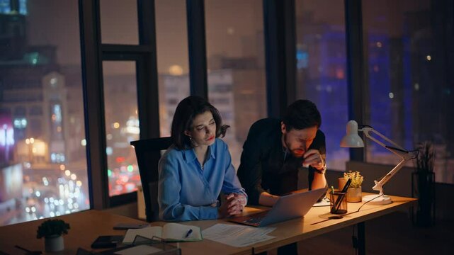Stressed coworkers failing deal at night workspace. Unhappy colleagues worried