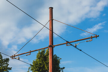 Rusty Overhead Catenary Support Pole against Bright Blue Sky