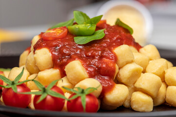 Close up on traditional italian potato gnocchi in tomato sauce with fresh basil and Cherry tomato