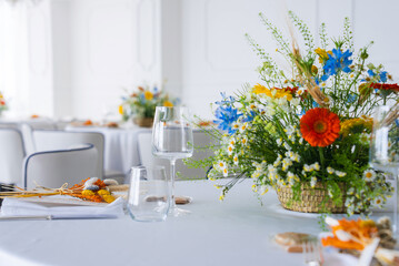 A bright dining table with a vibrant floral centerpiece, glassware, and white napkins in a refined interior, likely in Amalfi, Italy.