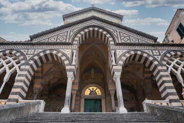 Obraz premium The Amalfi Cathedral features Romanesque, Byzantine, and Gothic styles, with striped arches, a golden mosaic, and a grand staircase under a clear sky.