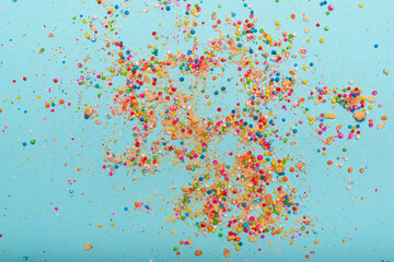Colorful sprinkles and cookie crumbs scattered across a light blue background