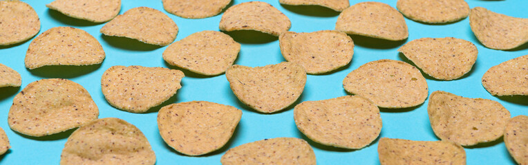 Numerous round nachos carefully arranged on a light blue-green background. Banner
