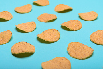 Numerous round nachos carefully arranged on a light blue-green background