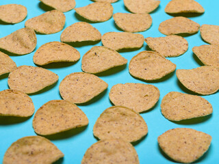 Numerous round nachos carefully arranged on a light blue-green background