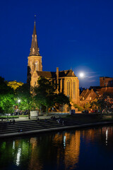 Naklejka premium Illuminated Historic Church by the River Maas in Maastricht at Night