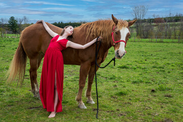 A young woman in a red dress with a horse