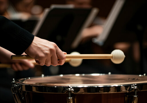 A close-up shot captures the intense focus of a musician playing the timpani during an orchestral performance