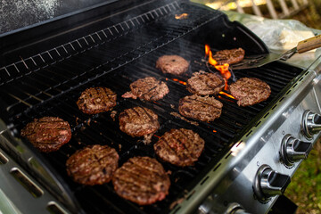 Burgers are cooking on a grill 