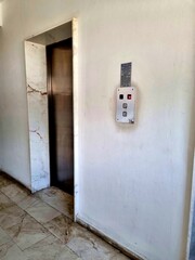 An elevator with closed stainless doors, marble frame, and wall-mounted control panel
