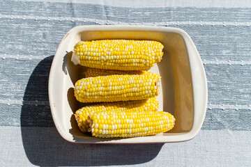 corn on the cob in a bowl on a grey table 