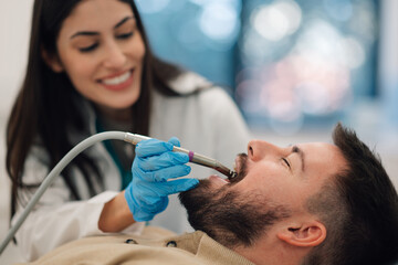 Female dentist performing dental procedure on male patient
