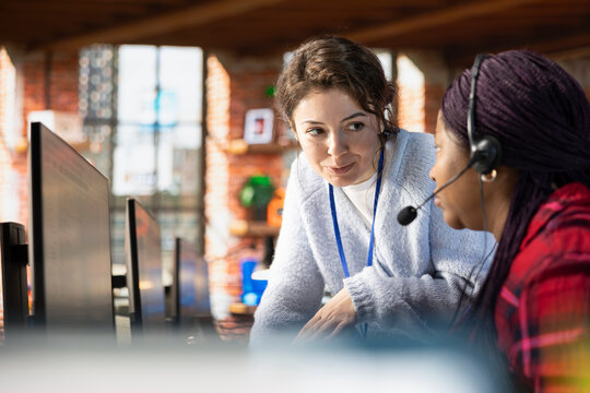 Smiling call center manager providing guidance to intern, addressing questions. Friendly customer support workplace onboarding specialist conducting orientation sessions for new worker