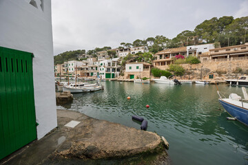 Cala figuera, majorca: picturesque fishing harbor with docked boats and white houses on a cloudy day