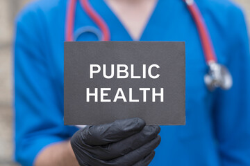 Doctor holding black paper card with inscription: PUBLIC HEALTH. Public health concept. Society...