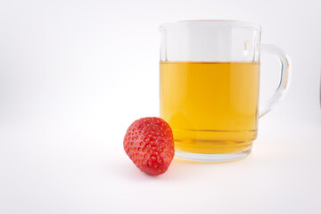 a clear glass mug of green tea beside vibrant strawberries evoking tranquility and healthy...