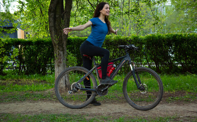 Beauty joy excited woman with long brown hair biking on bicycle on spring trees background and...