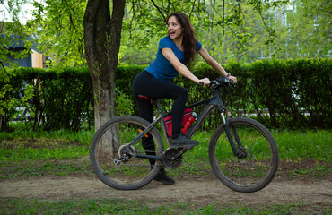 Beauty joy excited woman with long brown hair biking on bicycle on spring trees background and...