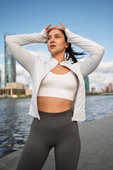 Sporty Woman Stretching Outdoors by the City Waterfront at Sunrise