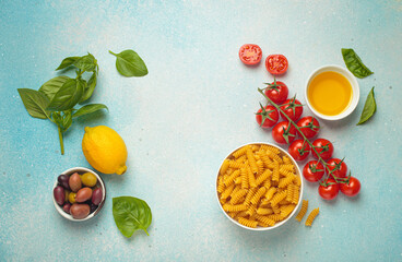 Fresh ingredients for preparing a traditional Italian pasta dish are arranged on a light blue...