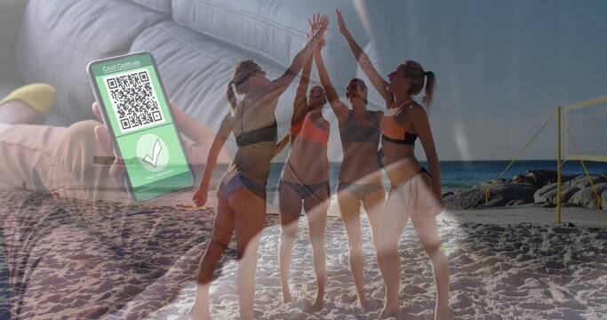 Image of caucasian woman with smartphone with covid passport over women on beach - Powered by Adobe