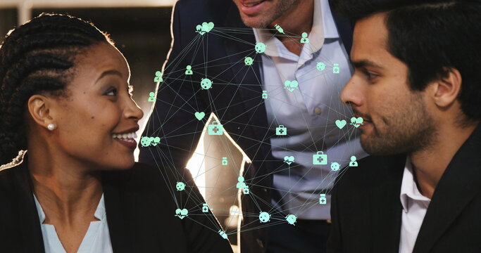 Globe of digital icons over three diverse male and female office colleagues discussing at office