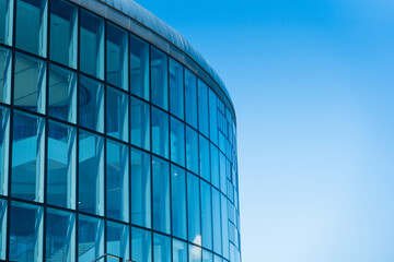 Contemporary architecture building with glass and metal facade on clear blue sky. For illustrating urban design or modern construction concepts. Copy space for text