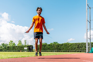 Athlete jumping rope on running track under blue sky