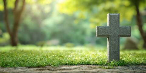 Stone grave cross in peaceful green cemetery surrounded by sunlight and trees in the background
