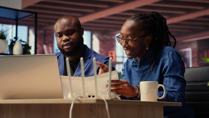 Black irritated man and woman rebooting their wireless router and checking network settings,...