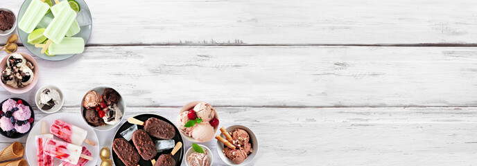 Cool summer food corner border. Assortment of ice cream bowls, popsicles and frozen treats. Overhead view on a white wood banner background. Copy space.