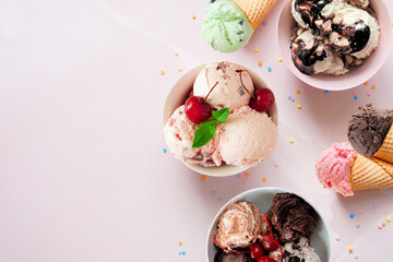 Summer ice cream side border. Bowls and cones of colorful assorted flavors. Top view on a soft pink stone background. Copy space.
