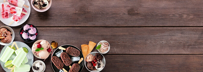 Cool summer food corner border. Variety of ice cream bowls, popsicles and frozen treats. Top view on a dark wood banner background. Copy space.
