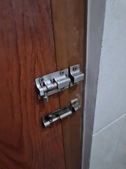 Two wooden door bolts side by side — one shiny and new, the other rusted — showing a striking contrast in age and durability.