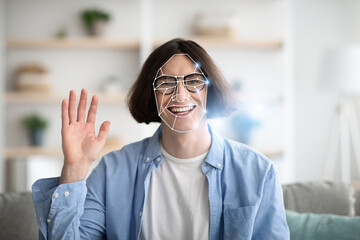 A person with a joyful expression waves while experiencing facial recognition technology at home....
