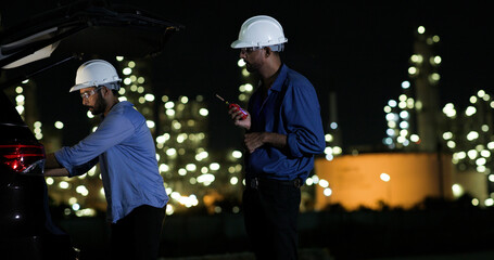 Two college Industrial engineer with white safety hat work with digital tablet and walkie talkie on night shift at Refinery and gas petrochemical plant, Industrial and business