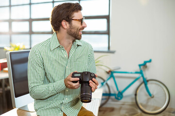 DSLR camera resting on white desk in studio by grid window, teal bicycle leaning against wall