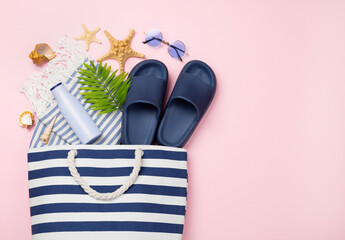 Blue beach bag with summer accessories on color background, top view
