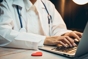 Fototapeta premium Health care concept. Medical Professional Working on Laptop with Stethoscope and Heart Symbol in Modern Healthcare Environment
