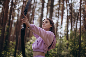 Young Brunette Aiming a Bow in the Forest