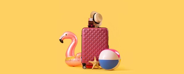 Suitcase and beach accessories on yellow background