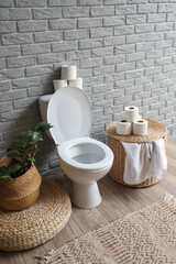 Interior of restroom with toilet bowl, pouf and basket
