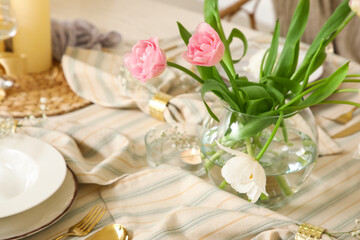 Vase with tulips on dining table in room, closeup