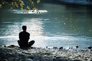 Obraz premium Man sitting at a riverbank