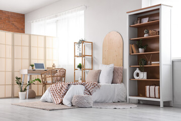 Interior of teenager's room with bed, shelf units and workplace